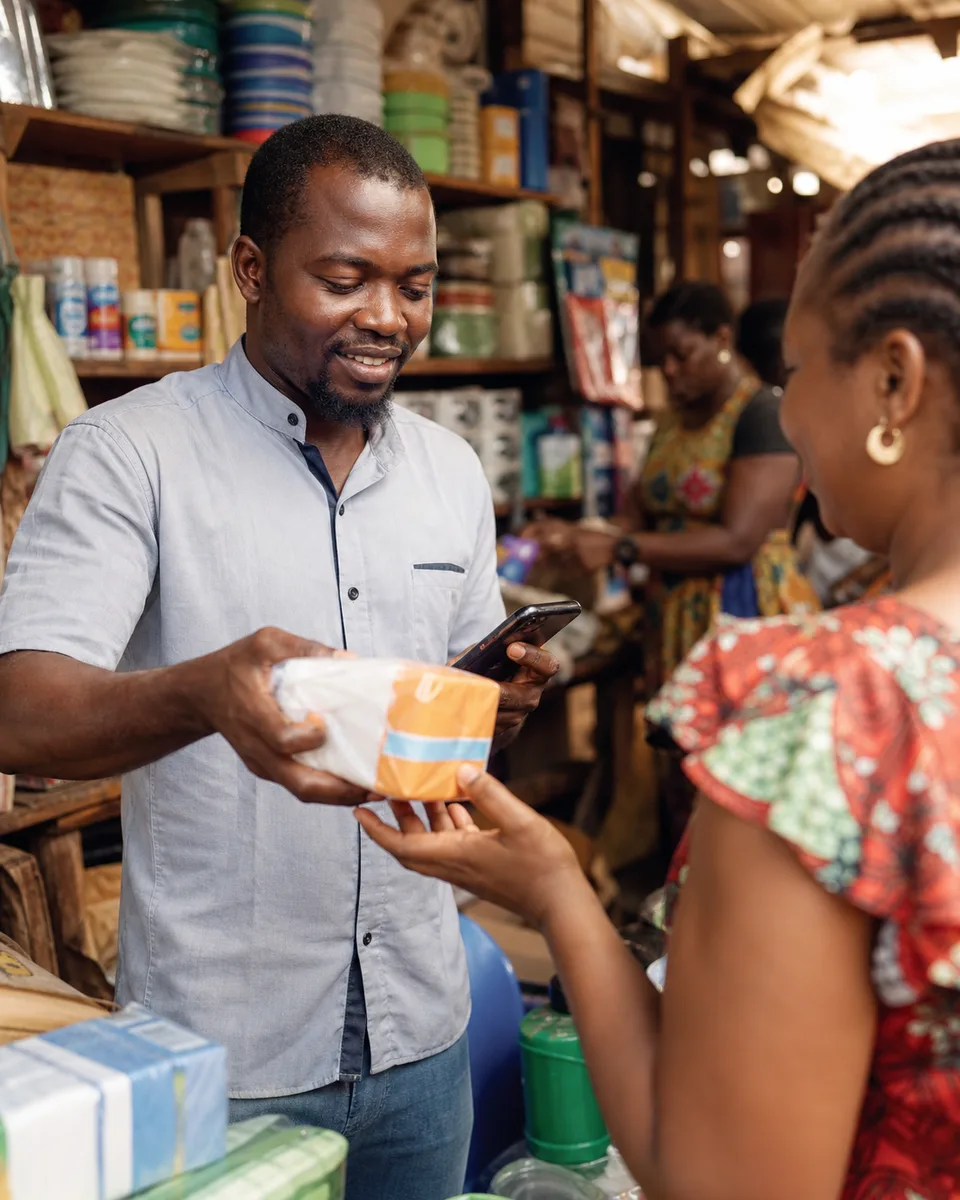 Cameroonian market merchant completing a mobile sale